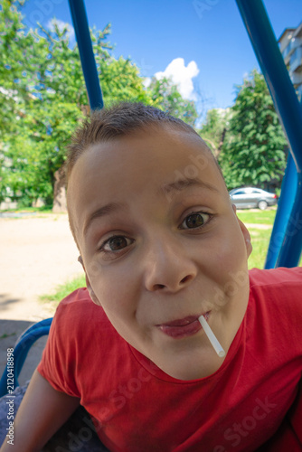 Happy playful boy with lollipop on outdoor playground in summer