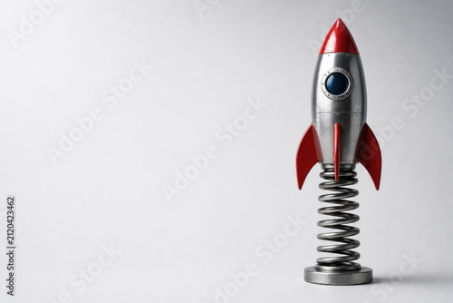 Retro rocket mounted on a large metal spring. Space for text.
