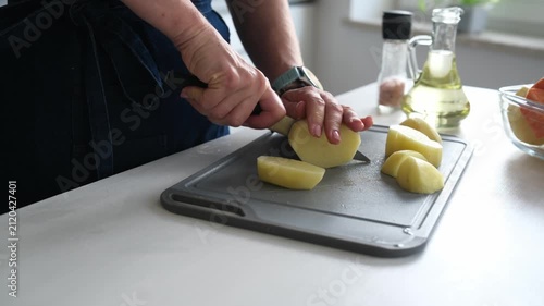 Woman Cutting Raw Potatoes In A Home Kitchen Close-Up Side View