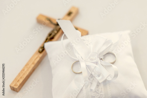 Wedding rings on pillow with wooden cross