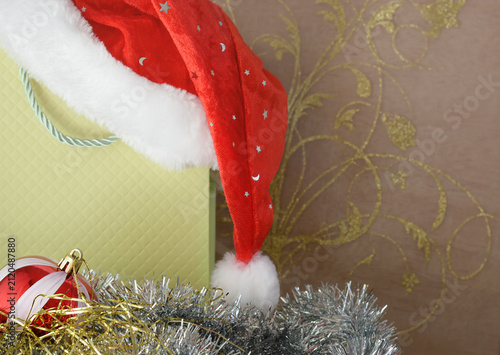 Christmas background with Christmas bauble, gift bag, and red Santa hat, with copy space