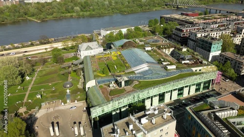 Top aerial shot of the University of Warsaw Library with glass roof panels, green garden areas, modern design and peaceful academic surroundings.
