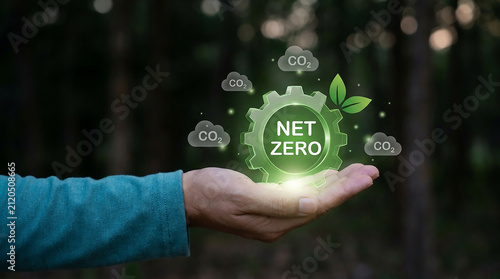 Net Zero Emissions Symbol Held in Hand: A hand gently cradles a glowing green gear with NET ZERO inscribed, symbolizing a commitment to environmental sustainability and a carbon-neutral future.