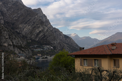 Mountain landscape overlooking Lake Garda with traditional Italian house and dramatic alpine peaks, Italy