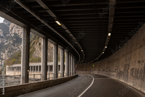 Curved Lakeside Road Passing Through an Open Tunnel in the Mountains
