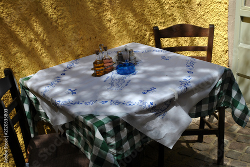 
A small table set for breakfast, with two chairs, stands outside in a narrow alley.