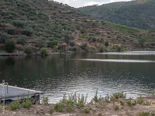 Peaceful view of the pier on the Tua River in São Mamede de Ribatua, Alijo, surrounded by rolling hills and the scenic Douro landscape at sunset.