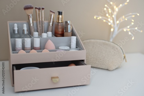 Fotografie Different makeup products in holder, bag and decor on white table indoors, close