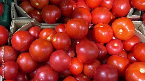 Fresh red tomatoes piled in cardboard boxes at market, showcasing vibrant colors and textures