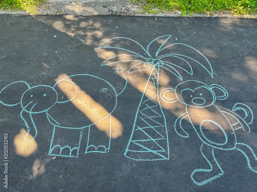 Photography Children's chalk drawing of a monkey and elephant beside a palm tree on asphalt, outdoor creativity, playful art and childhood imagination