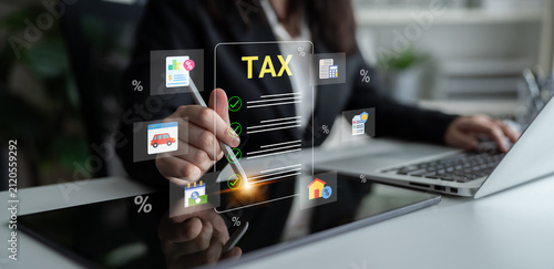 Canvas Print A business professional engages with tax documents while utilizing a digital interface featuring icons representing various financial elements in an office environment