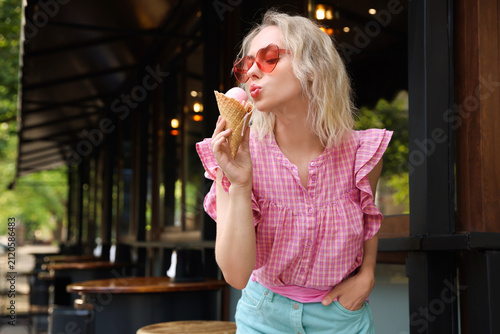Obraz na płótnie Beautiful woman in sunglasses posing with waffle cone with delicious ice cream at outdoor cafe