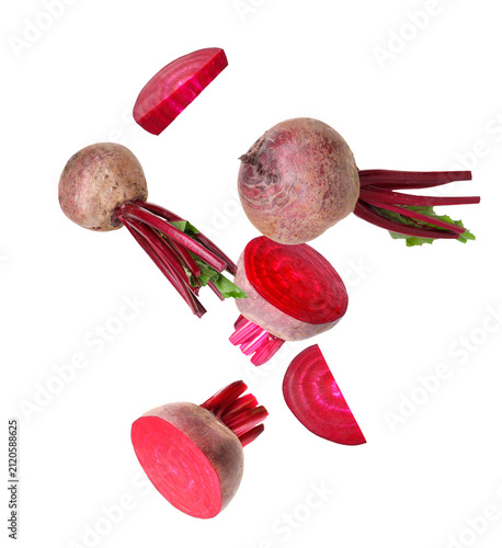 Canvastavla Sliced and whole beets flying in air against white background