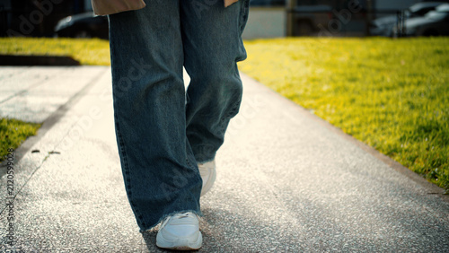 Close-up of an anonymous woman's feet walking on the street, representing movement, urban lifestyle, mobility, and everyday activity.