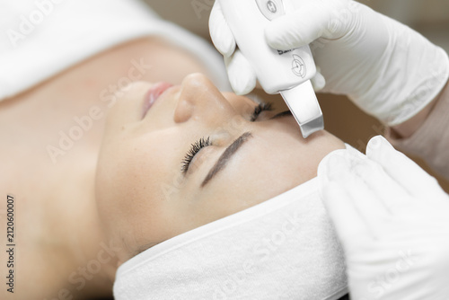 Closeup of female client undergoing ultrasonic face cleansing by skilled esthetician in spa setting. Innovative beauty technology enhances skin texture and promotes a healthy, glowing complexion