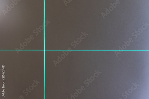 Foto green lines on a wall, made by a laser level mounted