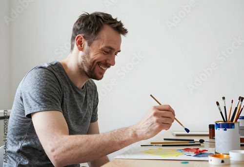 Smiling man painting with a...
