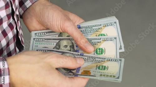 A person counts a stack of hundred dollar bills, highlighting themes of money management and financial planning. The image conveys concepts of investment, savings, and personal finance