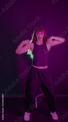 Young energetic woman dancing in neon light