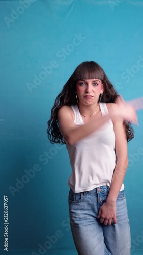 Energetic young woman dancing to music against a blue background