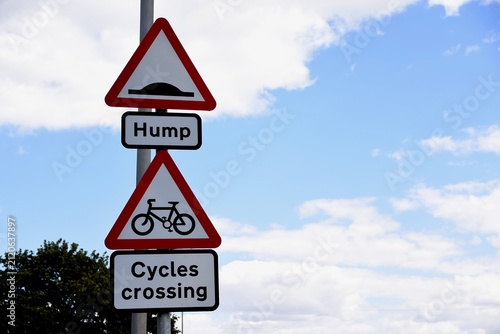 Road sign. Hump in the road and cycles crossing.
Blue cloudy sky