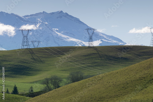 Foto View of the snow-capped Mount Ruapehu peak rising above the rolling green pastoral hills of the Ruapehu District, New Zealand