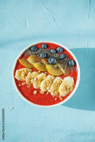 healthy smoothie bowl with granola, banana and fresh blueberries on color background