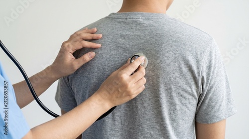 Doctor using stethoscope to examine patient's back during medical checkup