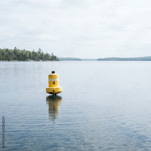 Yellow Buoy Floating on Calm Lake Water with Forested Shoreline.