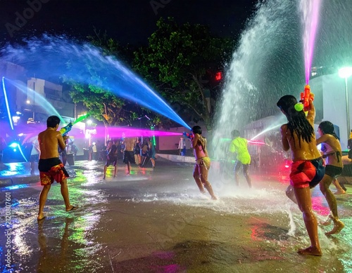 Friends playing with water guns during night festival