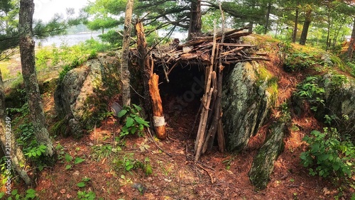 Scenic view of a makeshift bushcraft survival shelter built near the rocky shores of Thompson Dam area in the Minnesota and Wisconsin border during a summer outdoor adventure.