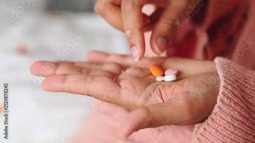 Hand holding four different pills in a home setting