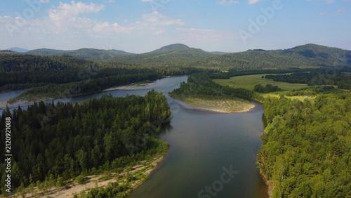 Aerial view of taiga river ecosystem surrounded by forest and mountains in summer. Natural environment with clean water and green vegetation. Concept of ecology, climate, conservation and environmenta