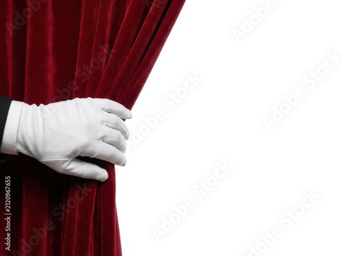 A Person In A White Glove Pulling Back A Red Velvet Curtain