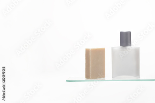 Fotografía Minimalist Men's Cleansing Set: A natural bar of soap stands next to a sleek, frosted glass aftershave bottle on a transparent shelf