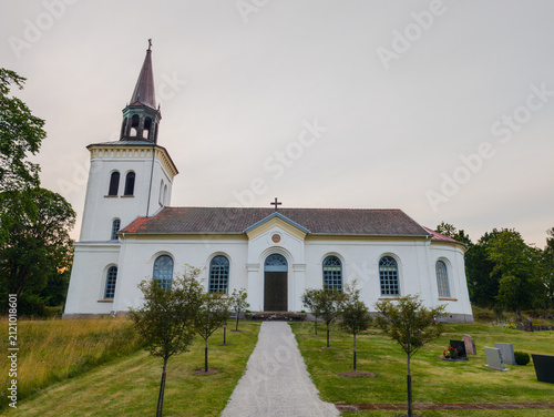 Foto Exterior view of the historic Fanneslunda-Grovare church surrounded by trees and a gravel pathway in Vastra Gotaland, Sweden