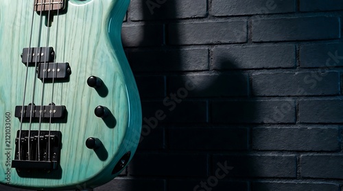 Close up of a teal electric bass guitar against a dark brick wall
