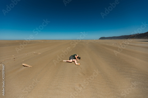 Person lying face down on a vast empty beach