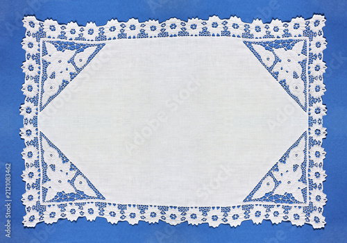 Retro white doily with openwork lace embroidery in Richelieu style with cut-out fragments on blue background. Frame with empty space for text. Closeup, top view, copy space, flat lay, blank, mockup