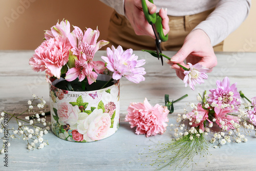 Florist at work: woman shows how to make flower box with alstroemerias, chrysanthemums and carnations in cute pink color, suitable for wedding or birthday present. Step by step, tutorial.