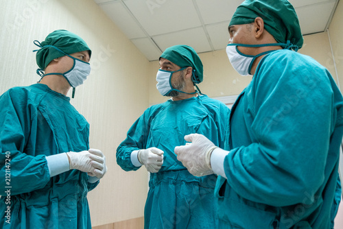 Surgery team in hospital corridor with masked surgeon and sterile green gown