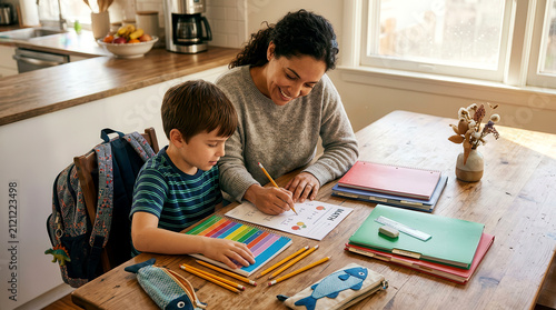 Mother helping her young son with math homework at a wooden dining room table