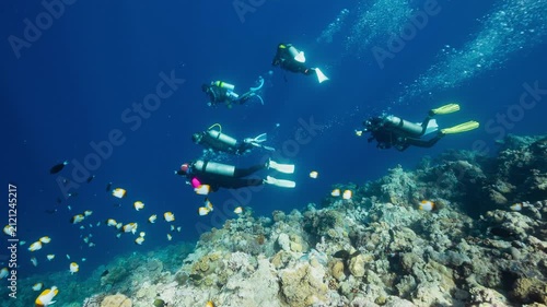 A group of SCUBA Divers descend down a reef into deep dark water	