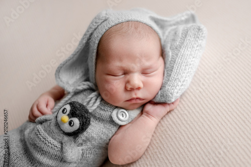 Newborn baby sleeps peacefully on soft cream blanket. Professional newborn photoshoot.