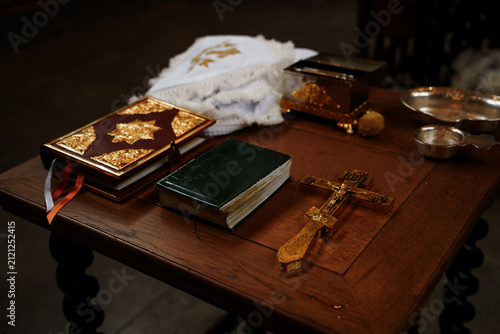 Cuadro en lienzo Ornate religious book and golden cross placed on a wooden table as Orthodox baptism attributes