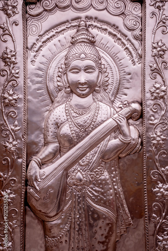 A silver sculpture of the Hindu goddess Saraswati playing the vina, adorned with floral motifs and jewelry, at the Shri Durgiana Temple.