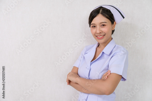 Smiling nurse portrait with arms crossed, studio background, Asian woman, uniform, healthcare