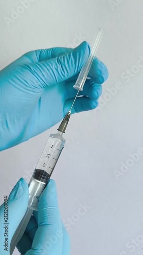 Healthcare worker removing protective cap from syringe with medication, preparing injection, medical treatment and healthcare concept.