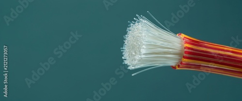 Exposed fiber optic cable with white strands and a red-yellow striped sheath on a teal background. Modern data.