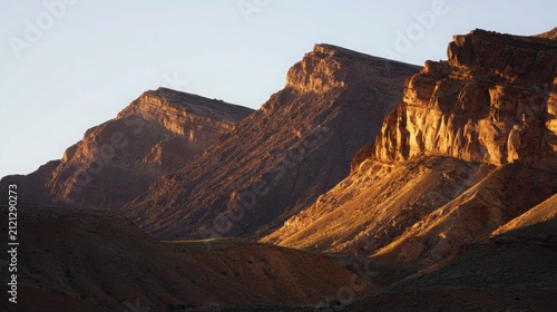 Rugged mountain ridges glowing under warm golden hour sunlight
